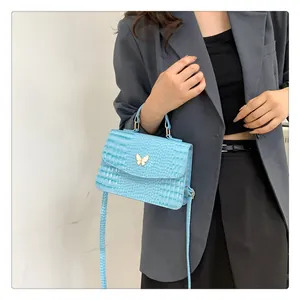 Detail of light blue crocodile embossed bag with gold butterfly clasp on model's shoulder
