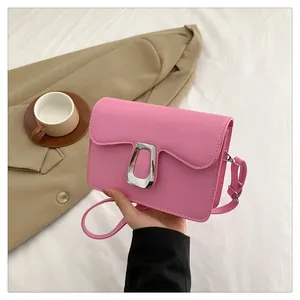 Close-up of pink leather crossbody bag featuring a wavy flap and silver metal buckle