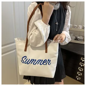Dettaglio della borsa in tela bianca con ricamo Summer blu e manici in pelle marrone