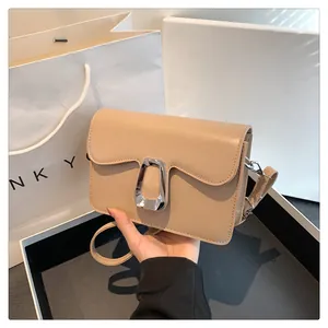 Detail shot of khaki square shoulder bag with wave-edge flap and silver metal buckle