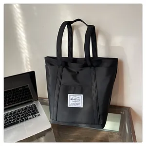 Detalle de un bolso tote grande de nailon negro con parche blanco para uso diario laboral