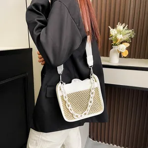 Detail view of woven straw crossbody bag with white chunky chain and fabric strap