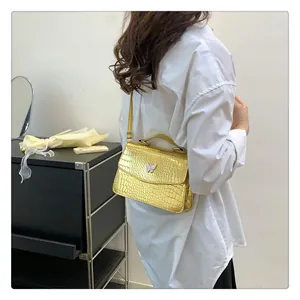 Close-up of golden crocodile texture shoulder bag with white butterfly emblem on the flap