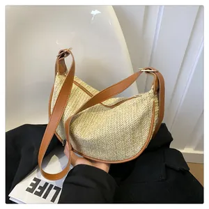 Detail of herringbone woven straw texture and brown leather trim on a crescent bag