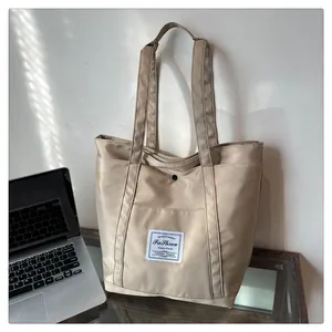 Detalle del bolso tote de nailon caqui con cierre de presión y parche de logotipo textil