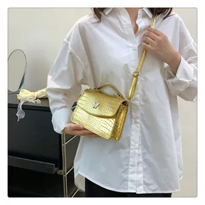 Detail of gold faux crocodile texture shoulder bag with white butterfly buckle and strap