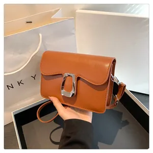 Detail of caramel square handbag with wavy flap and silver metallic buckle