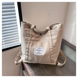 Detalle del bolso de nailon beige con bolsillo frontal y cierre de botón a presión