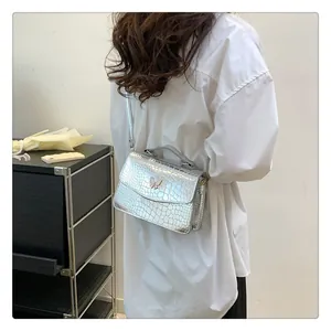 Close-up of silver crocodile embossed bag with elegant gold butterfly metal clasp detail