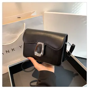 Close-up of black leather square bag featuring a vintage silver buckle and slim strap