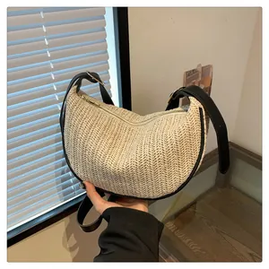 Close-up of beige woven half-moon bag with black leather strap and golden zipper