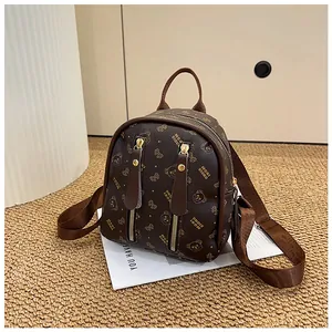 Detail of a brown mini backpack featuring bear monogram patterns and vertical zippers