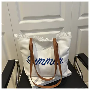 Dettaglio della borsa tote in tela bianca con testo Summer blu e manici in pelle
