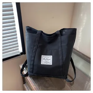 Detalle de bolso tote de nailon negro con etiqueta textil blanca y cierre metálico
