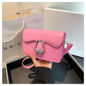 Detail of a bright pink square crossbody bag featuring a silver trapezoidal buckle