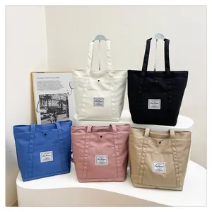 Vista detallada de bolsos tote de nailon de moda en varios colores sobre un pedestal