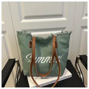 Dettaglio della borsa tote in tela verde con ricamo Summer e manici in pelle marrone