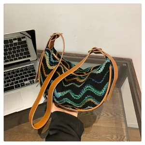 Detail of multi-color woven knit texture and brown leather strap on crescent bag