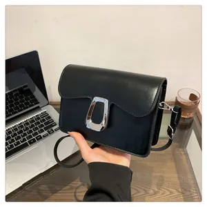 Detail of black square crossbody bag featuring a matte finish and silver U-shaped metal buckle