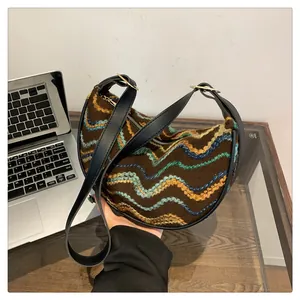 Detail view of woven shoulder bag featuring vibrant wavy stitching and gold ring hardware