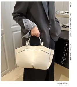 Detail of cream tote bag with black contrast piping shown on a model in professional suit