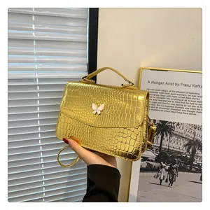 Detailed close-up of metallic gold crocodile textured bag with white butterfly ornament