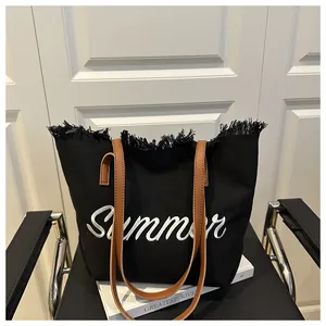 Dettaglio borsa tote in tela nera con ricamo Summer e bordi decorati con frange