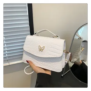 Detail of white crocodile texture leather bag with elegant golden butterfly clasp