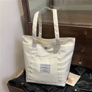 Bolso tote minimalista de nailon blanco crema con gran bolsillo frontal y asas