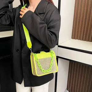 Detail view of woven straw crossbody bag with neon green flap and bold chain strap