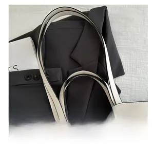 Detailed view of comfortable shoulder straps on a minimalist cream tote bag with black trim