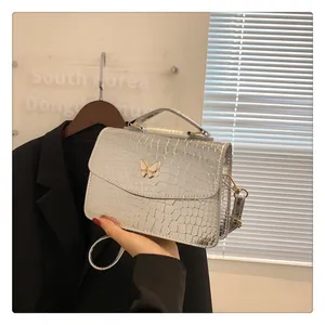 Close-up of silver faux crocodile embossed handbag with a metallic butterfly ornament