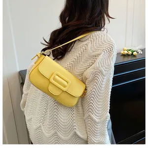 Side view of model wearing a bright yellow shoulder bag with a large decorative buckle