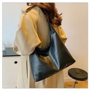 Detail of black faux leather tote bag showing soft texture and stitching on the shoulder