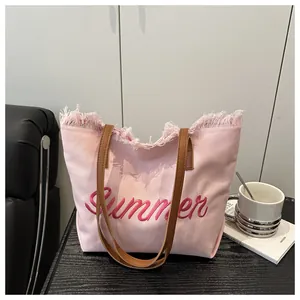 Dettaglio della borsa tote in tela rosa con ricamo Summer rosso e manici in pelle