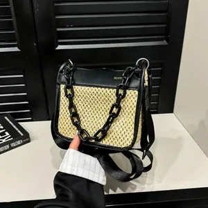 Detail of woven straw texture and black leather contrast on a modern crossbody bag