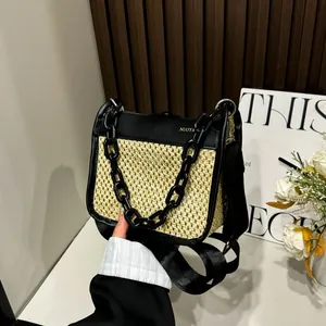 Detail view of straw woven bag with black leather flap and gold chain strap handle