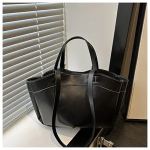 Close-up of black leather tote bag with stylish white contrast stitching and dual straps