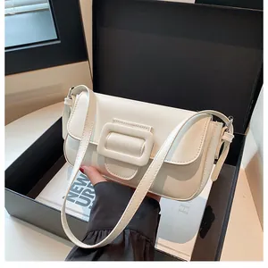 Close-up of white minimalist leather baguette bag with square buckle in a black gift box