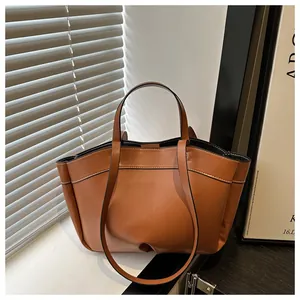 Detail of caramel brown tote bag featuring white contrast stitching and long shoulder strap