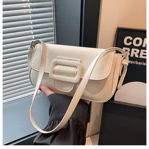 Close-up of minimalist white leather baguette bag with oversized buckle and adjustable strap