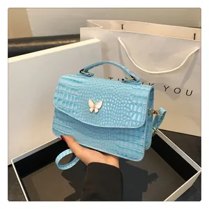 Close-up of light blue crocodile texture bag with white enamel butterfly metal clasp
