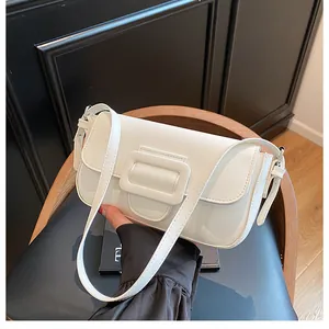 Detail of a retro cream baguette bag featuring a large square buckle and leather texture