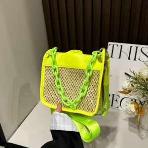 Detail of woven straw handbag with neon yellow-green leather trim and chunky chain strap
