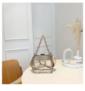 Dettaglio borsa in PVC trasparente con bordo in strass e ampia tracolla in raso dorato