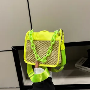 Detail of neon green straw crossbody bag featuring a thick chain and adjustable strap