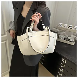 Close-up of a white leather tote bag with black edge paint and H-shaped stitching detail