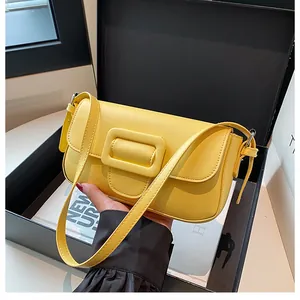 Detail of bright yellow baguette bag with a square buckle on a black gift box