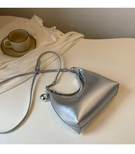 Détail du sac croissant argenté avec breloque boule en métal et fini brillant