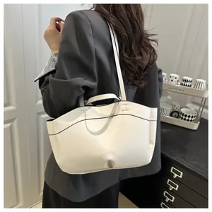 Cream large capacity tote bag worn on shoulder by model in a minimalist office setting
